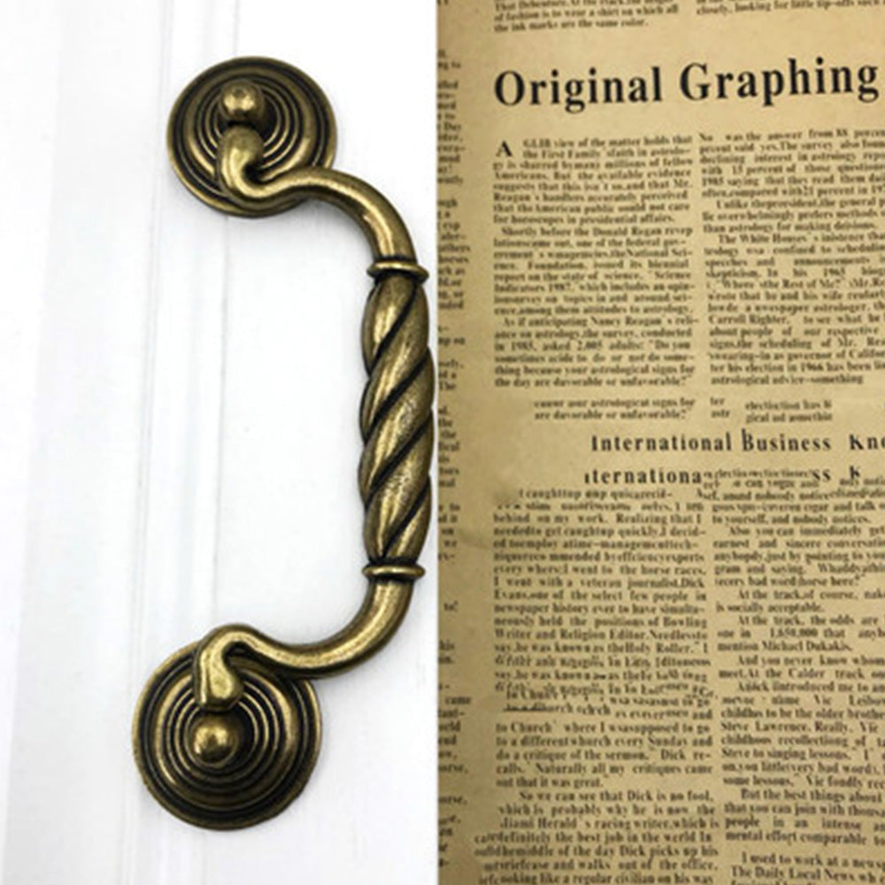 Vintage twisted bail drawer pull with rosette mounts, pictured in one view installed on cabinetry in context