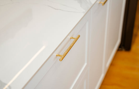 Close-up of a brass cabinet pull on a white drawer for cabinet pull size guide
