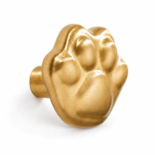 Natural brass cat paw cabinet knob with raised paw pads on a white background