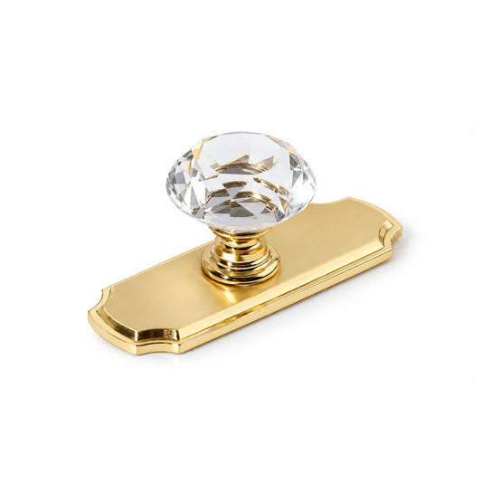 Clear faceted crystal cabinet knob with a gold-tone decorative backplate on white