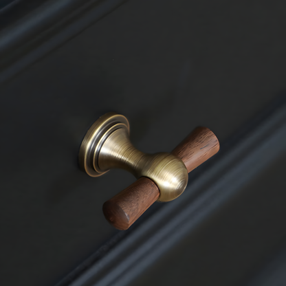 Wood T-bar cabinet pull with round metal pedestal mounts, shown from one angle in an installed cabinet close-up