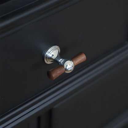 Wood T-bar cabinet pull with round metal pedestal mounts, presented for reference in an installed cabinet close-up