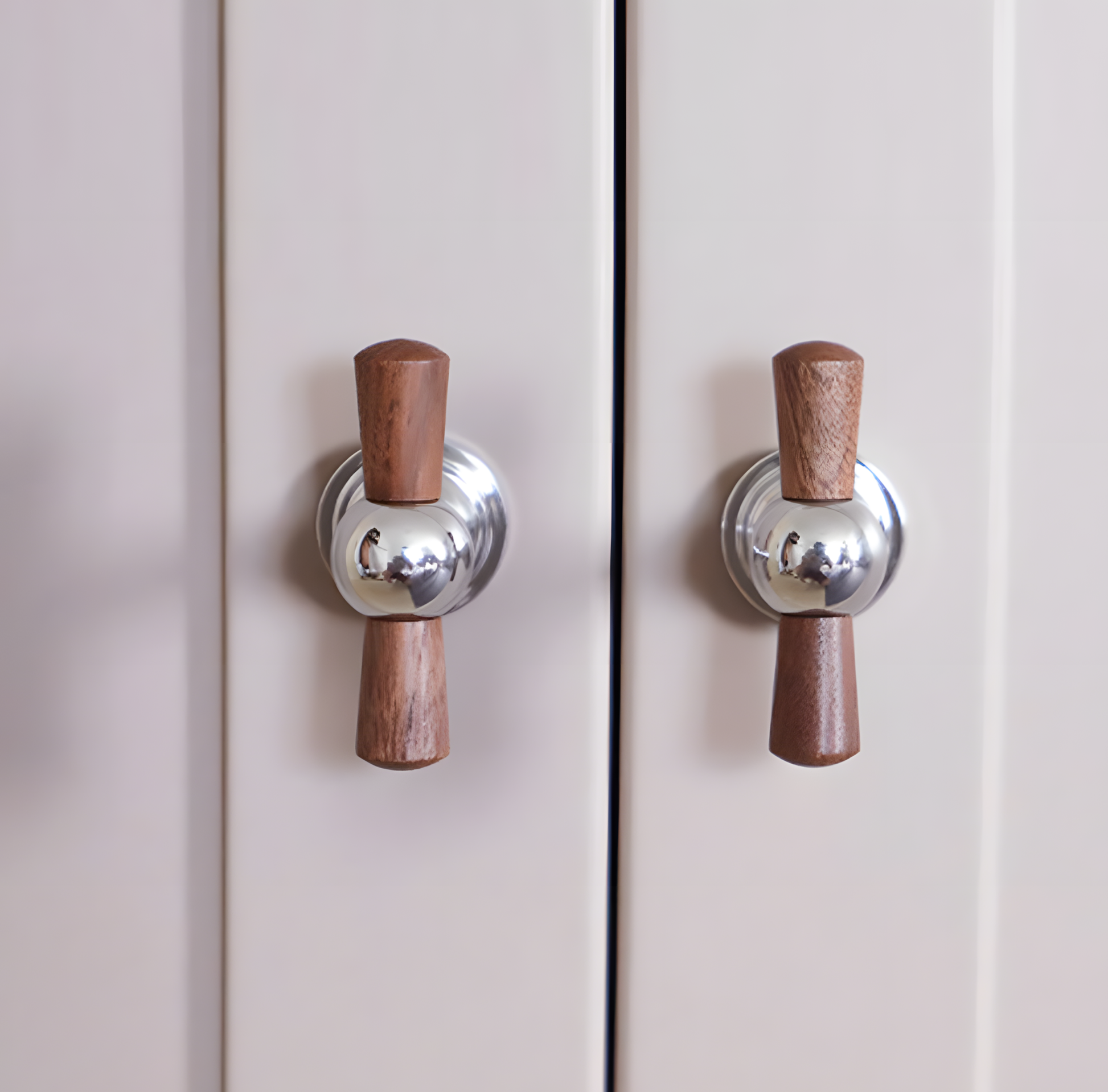Wood T-bar cabinet pull with round metal pedestal mounts, shown at close range mounted on a finished cabinet front