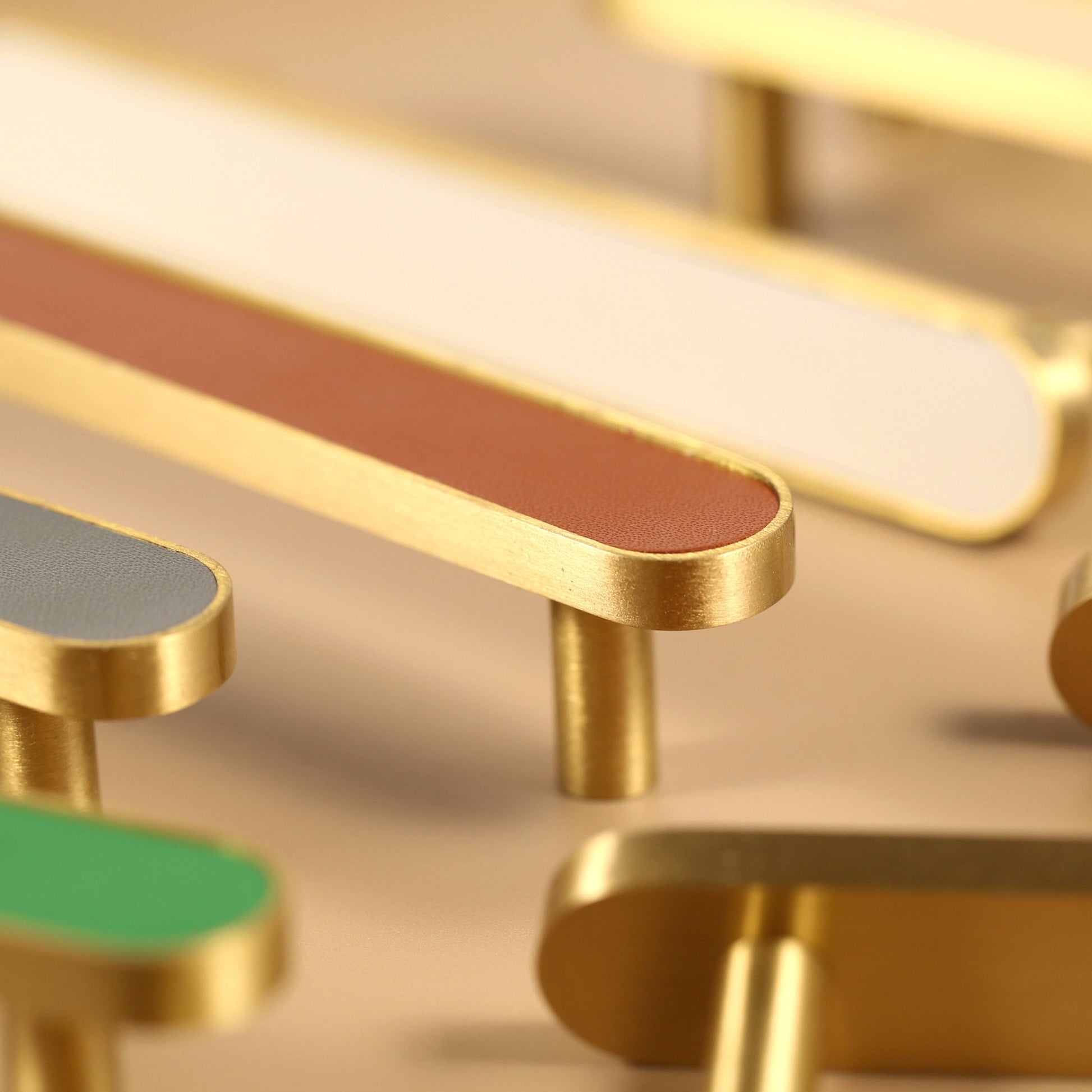 Close side view of a brown leather-inlay cabinet pull with a gold-tone frame and round posts