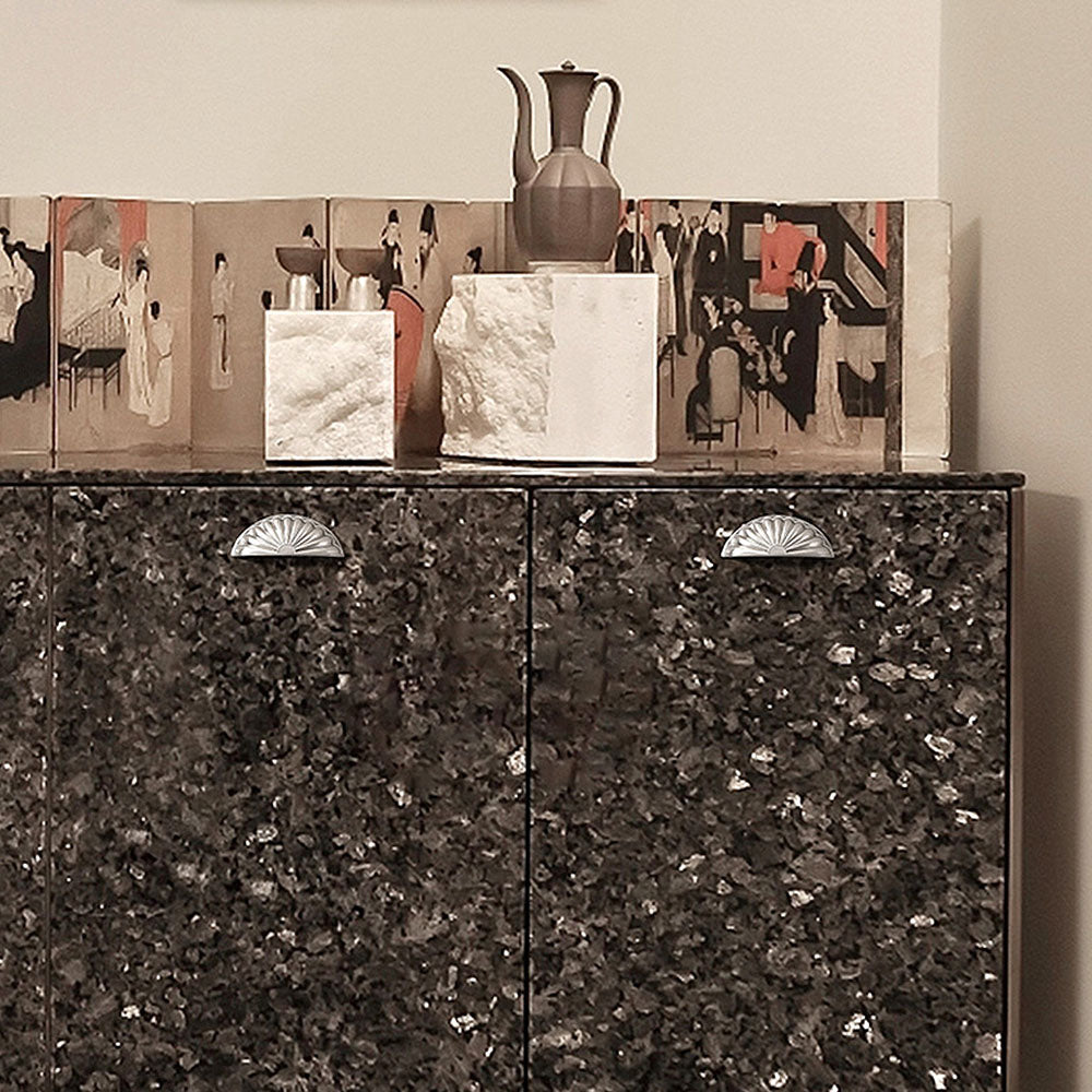 Shell-shaped cabinet cup pull, shown in a focused view installed on cabinetry in context
