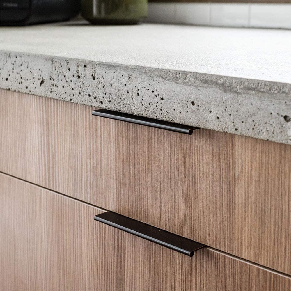 Black square aluminum cabinet edge pull, shown from one angle installed on cabinetry in context