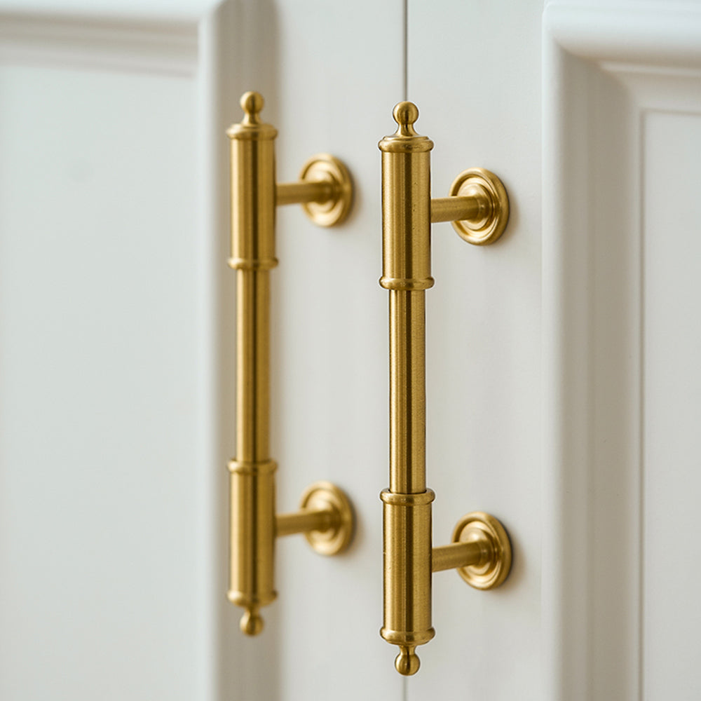 Antique brass round bar cabinet pull with matching T-knob, shown at close range in an installed cabinet close-up
