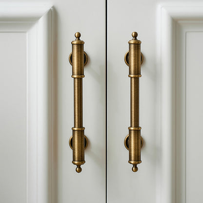 Antique brass round bar cabinet pull with matching T-knob, shown in a focused view in an installed cabinet close-up