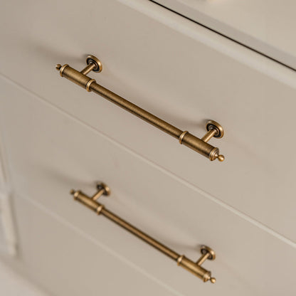 Antique brass round bar cabinet pull with matching T-knob, pictured in one view installed on cabinetry in context