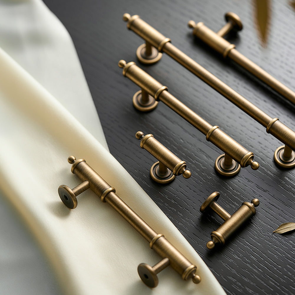 Antique brass round bar cabinet pull with matching T-knob, pictured in one view as a color and finish lineup