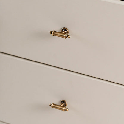 Antique brass round bar cabinet pull with matching T-knob, shown at close range installed on cabinetry in context