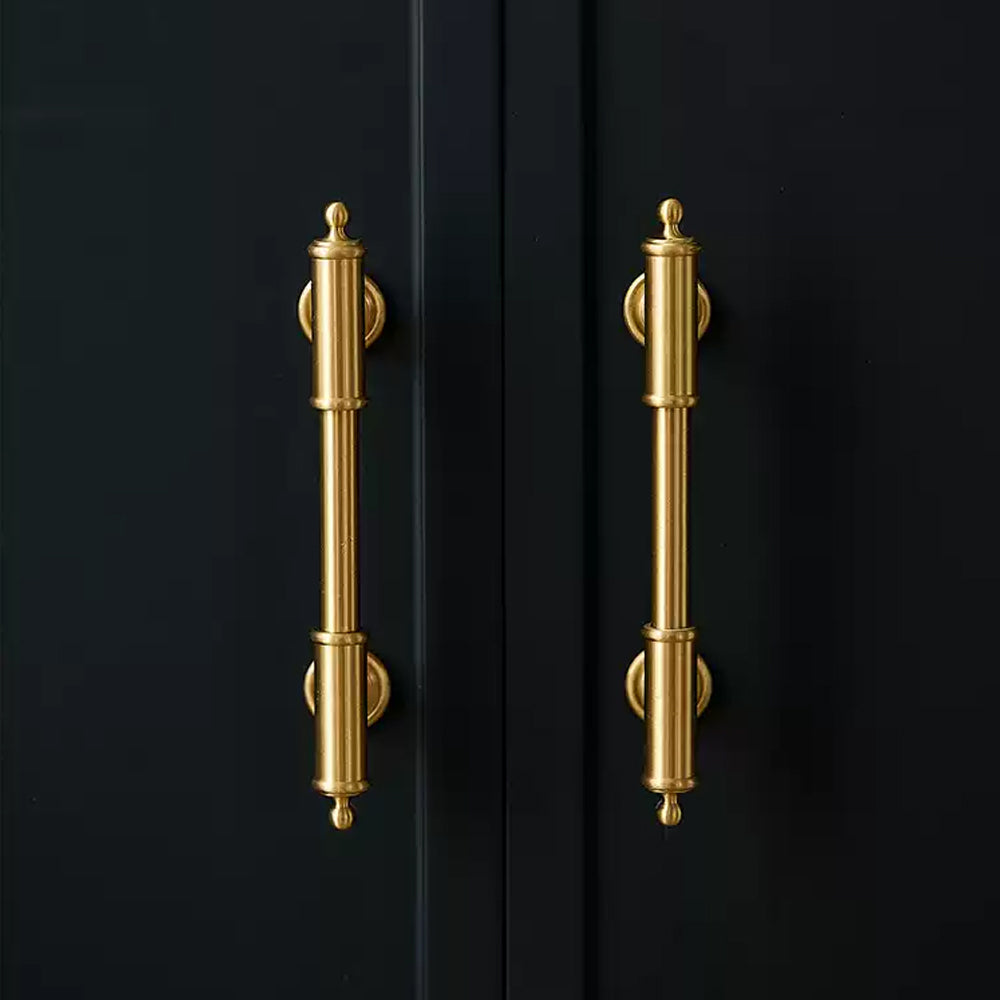 Antique brass round bar cabinet pull with matching T-knob, shown from one angle in an installed cabinet close-up