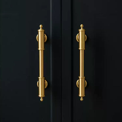 Antique brass round bar cabinet pull with matching T-knob, shown from one angle in an installed cabinet close-up