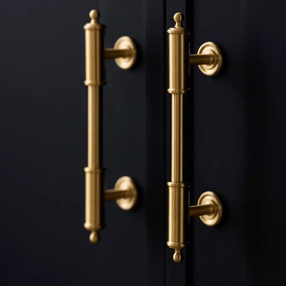Antique brass round bar cabinet pull with matching T-knob, pictured in one view in an installed cabinet close-up