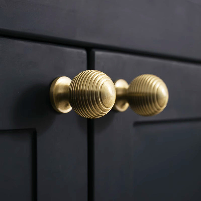 Antique bronze cabinet pull with matching ribbed knob, shown in a focused view in an installed cabinet close-up