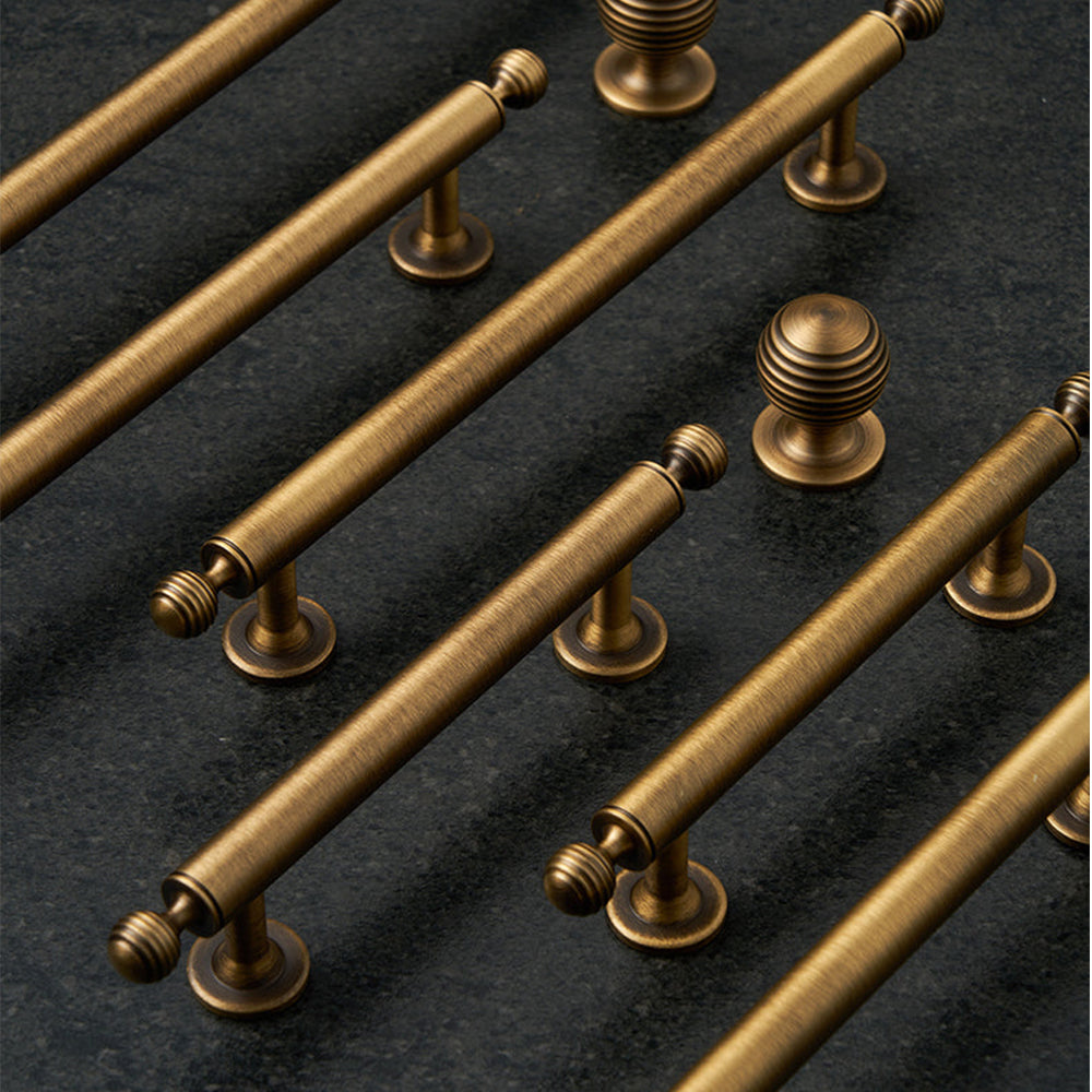 Antique bronze cabinet pull with matching ribbed knob, shown from one angle as a color and finish lineup