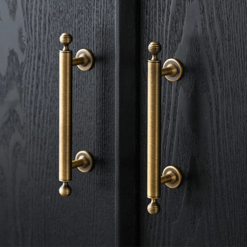 Antique bronze cabinet pull with matching ribbed knob, shown from one angle in an installed cabinet close-up