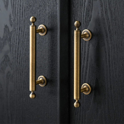Antique bronze cabinet pull with matching ribbed knob, shown from one angle in an installed cabinet close-up