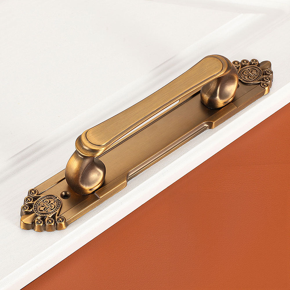Antique bronze cabinet pull with decorative floral backplate, shown from one angle on a clean neutral background