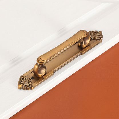 Antique bronze cabinet pull with decorative floral backplate, shown at close range on a clean neutral background