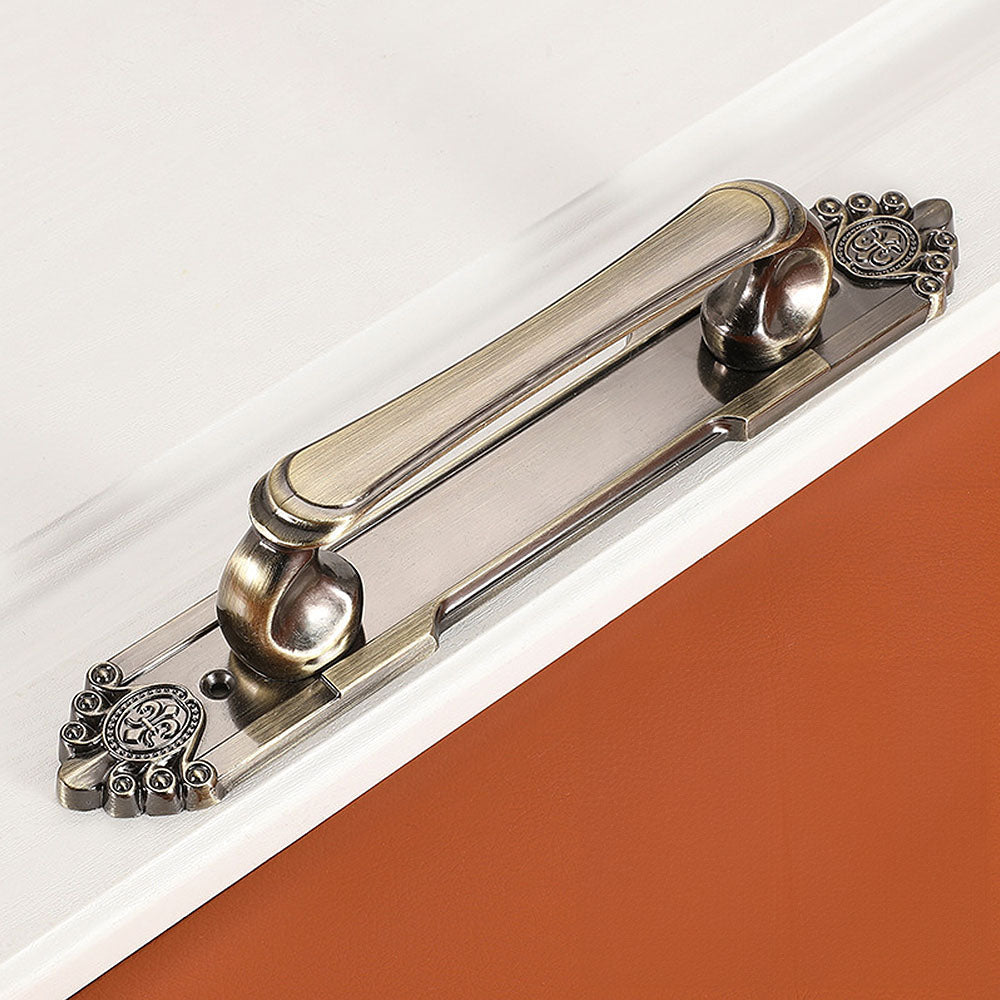Antique bronze cabinet pull with decorative floral backplate, displayed from the side on a clean neutral background