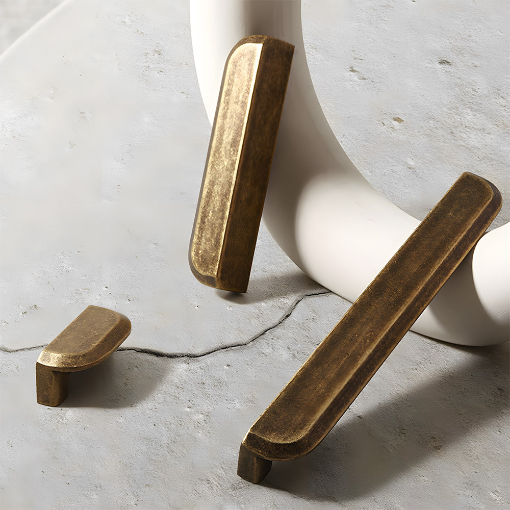 Antique bronze recessed cabinet pull, shown from one angle with related hardware in one display