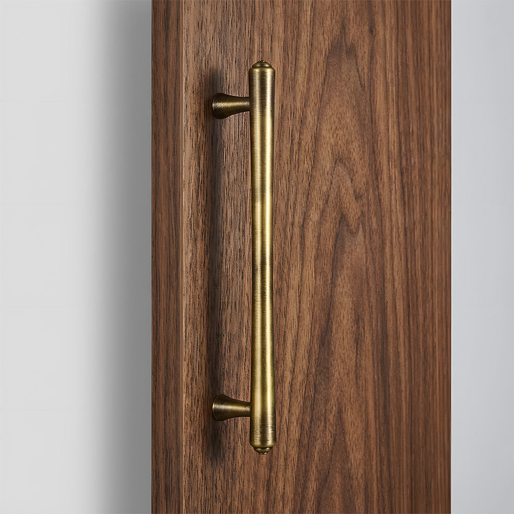 Antique bronze round bar cabinet pull, shown from one angle in an installed cabinet close-up