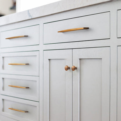 Arched aluminum cabinet pull, presented in another view installed on cabinetry in context