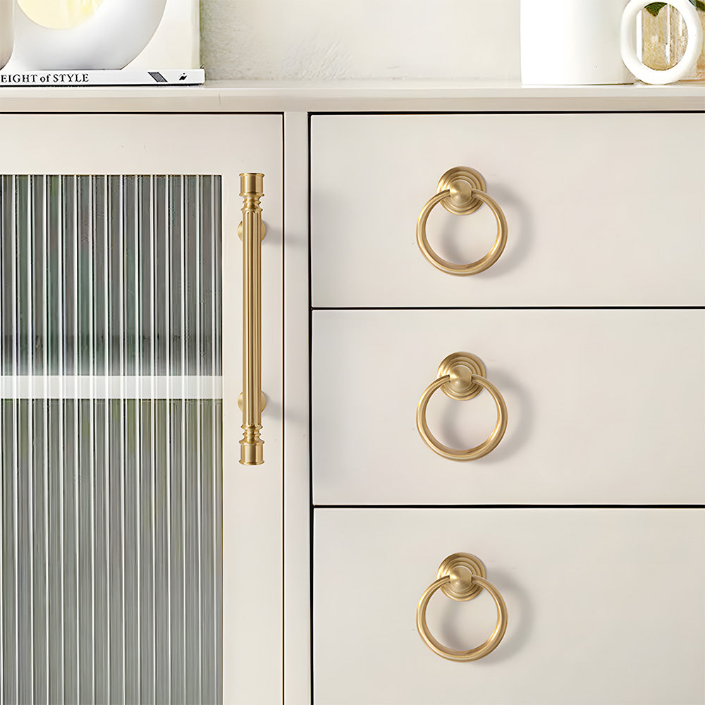 Gold art deco fluted brass pulls, knobs, and ring pulls, pictured in one view installed on cabinetry in context