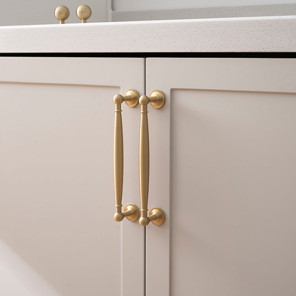 Gold brass round bar cabinet pull and round knob, shown clearly installed on cabinetry in context