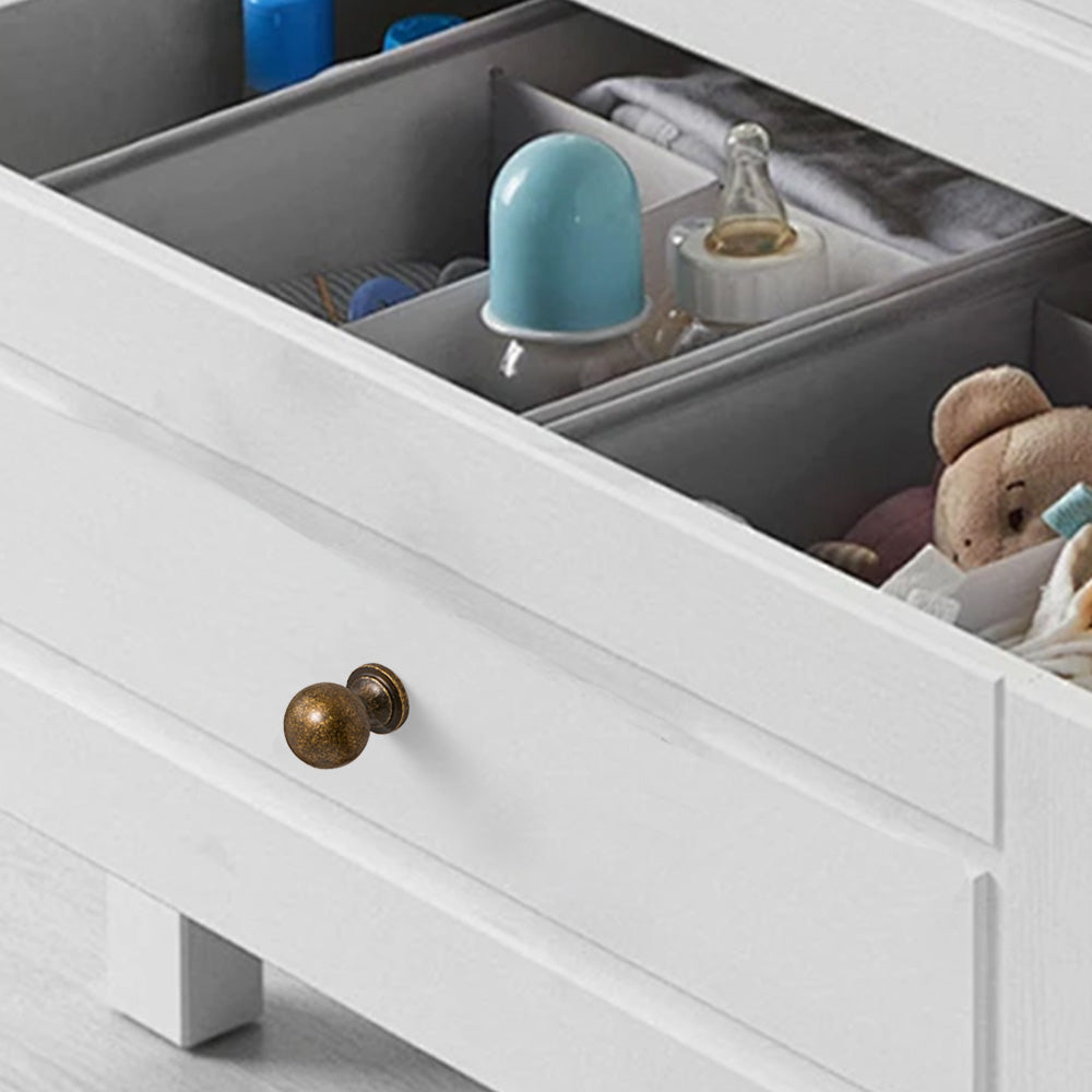 Bronze brass round bar cabinet pull and round knob, shown in a focused view installed on cabinetry in context