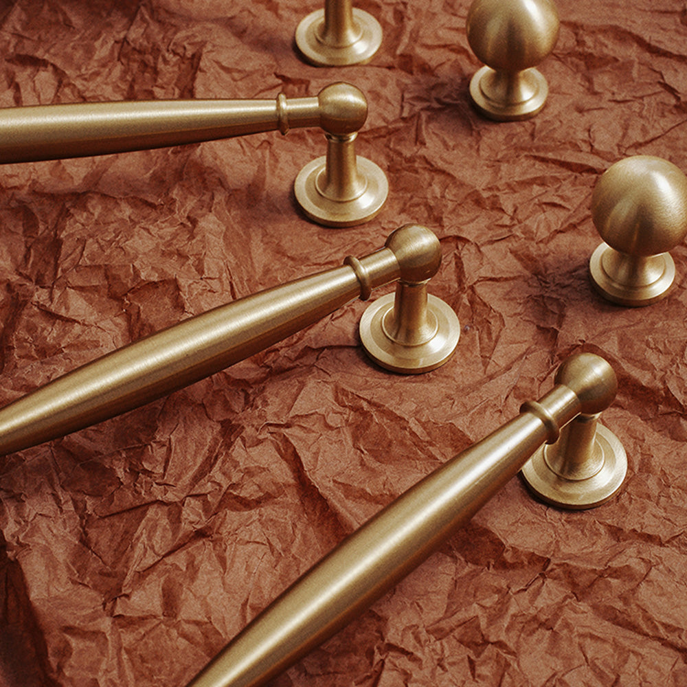 Brass round bar cabinet pull and round knob, shown clearly in an installed cabinet close-up