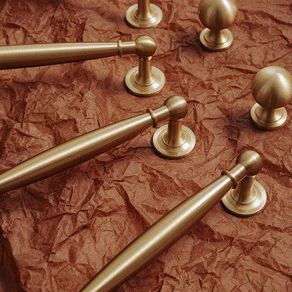 Brass round bar cabinet pull and round knob, shown clearly in an installed cabinet close-up
