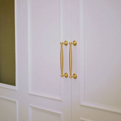 Gold brass round bar cabinet pull and round knob, shown from one angle installed on cabinetry in context