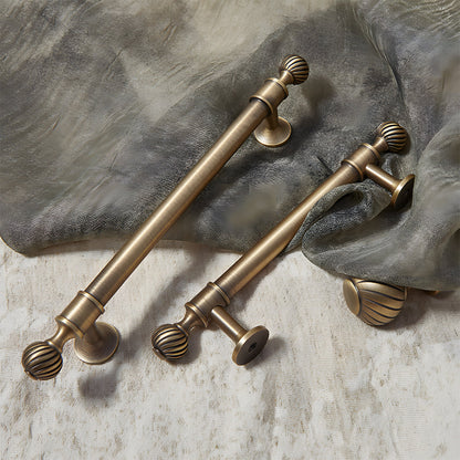 Bronze ribbed brass cabinet pull and shell knob, presented for reference with related hardware in one display