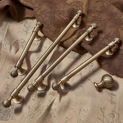 Ribbed brass cabinet pull and shell knob, shown clearly with related hardware in one display