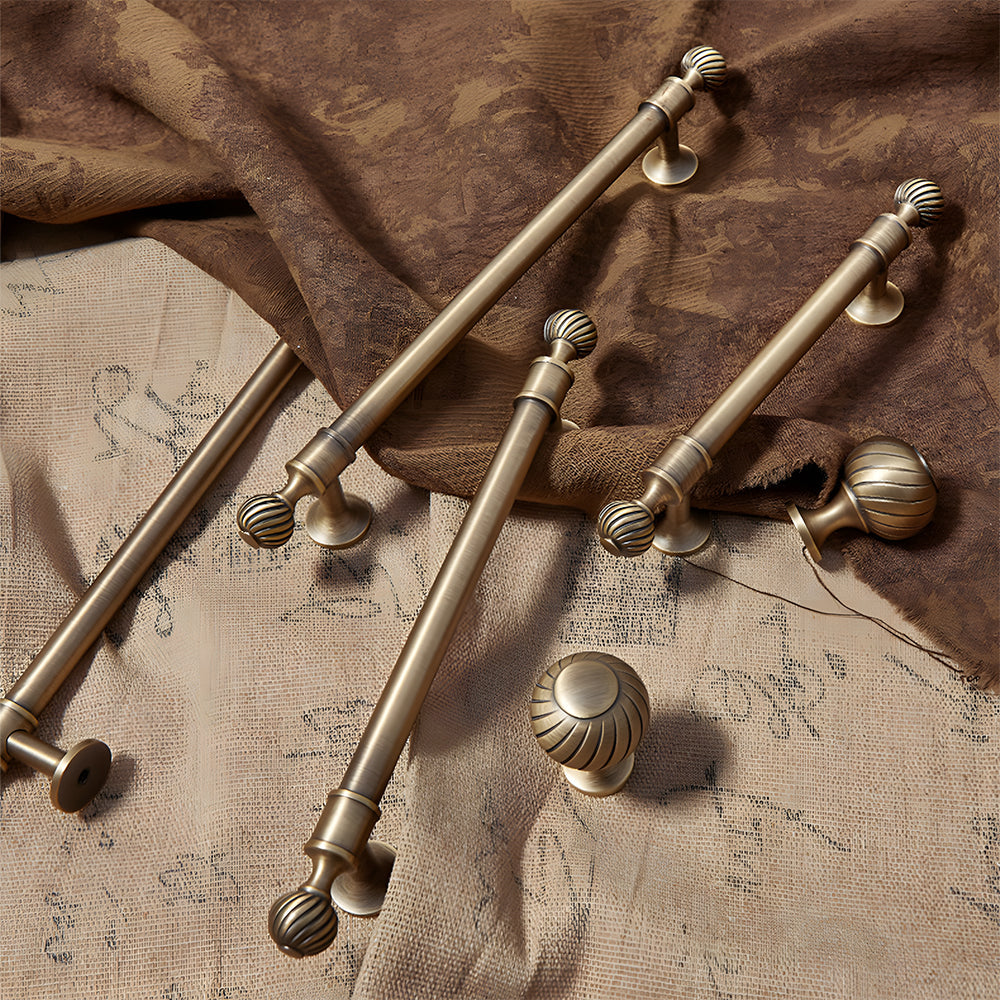 Ribbed brass cabinet pull and shell knob, shown from one angle with related hardware in one display
