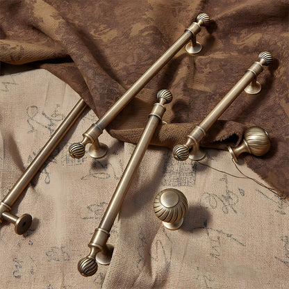Ribbed brass cabinet pull and shell knob, shown from one angle with related hardware in one display