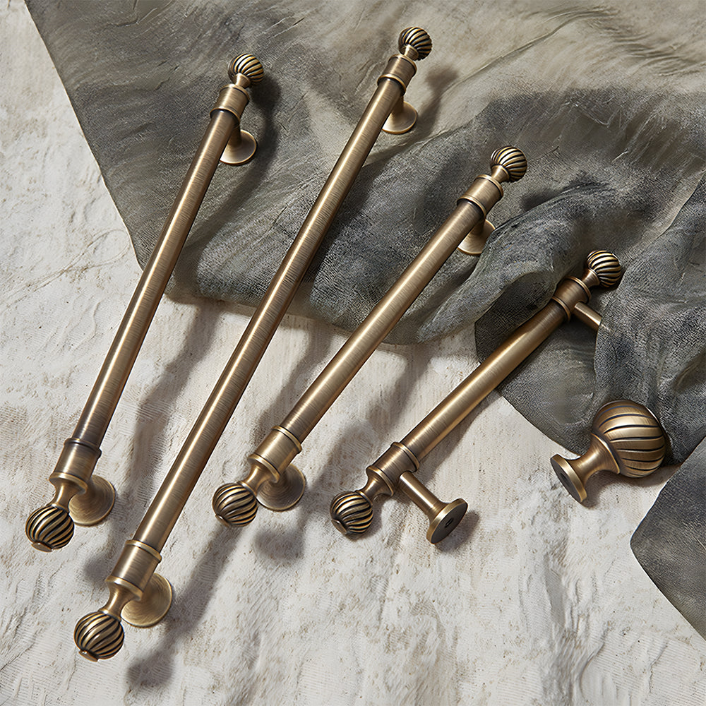 Ribbed brass cabinet pull and shell knob, pictured in one view with related hardware in one display