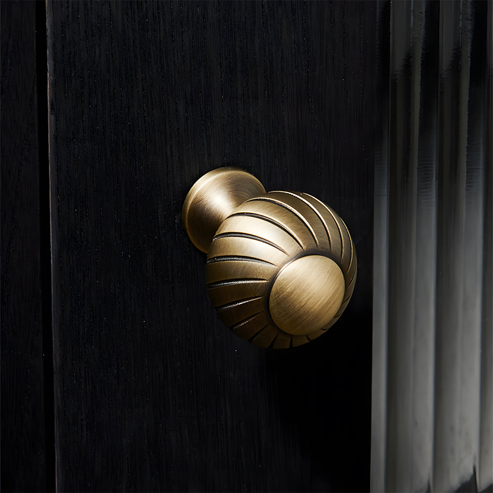 Bronze ribbed brass cabinet pull and shell knob, pictured in one view in an installed cabinet close-up