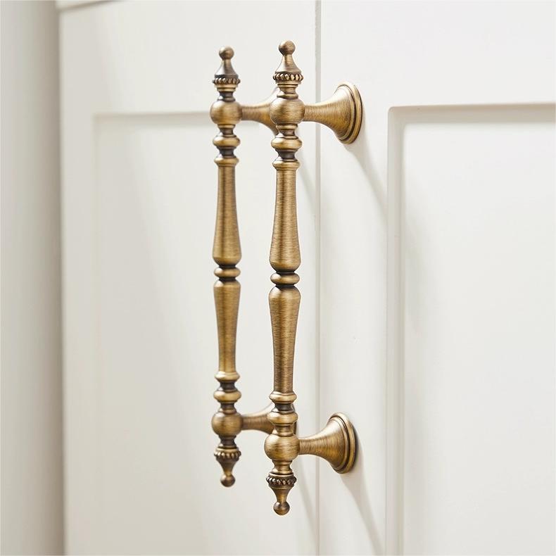 Ornate brass cabinet pull and knob, shown clearly in an installed cabinet close-up