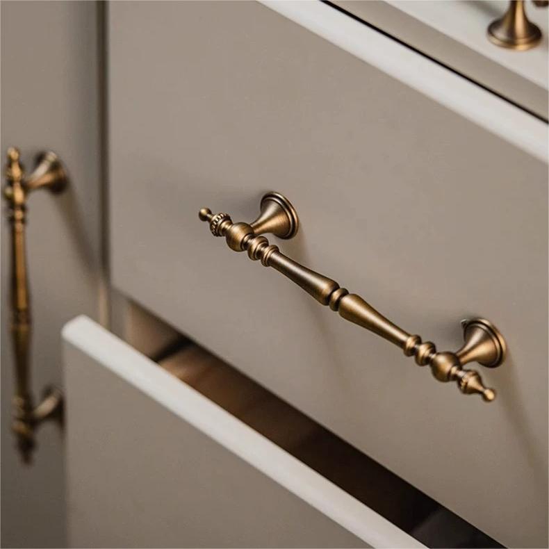 Ornate brass cabinet pull and knob, shown clearly installed on cabinetry in context