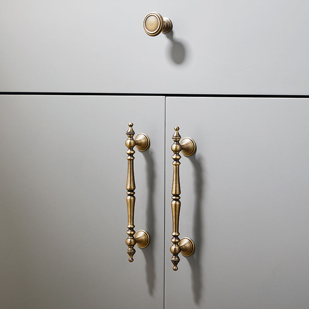 Bronze ornate brass cabinet pull and knob, pictured in one view in an installed cabinet close-up