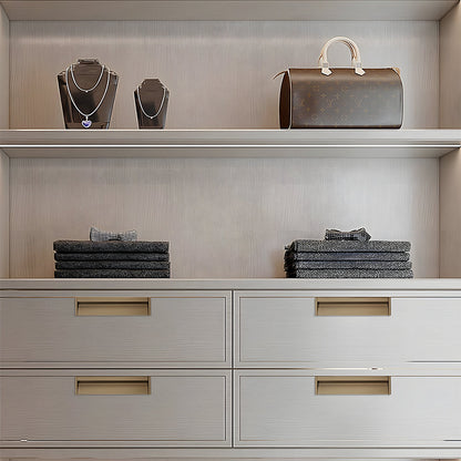 Bronze aluminum recessed cabinet pulls with 128 mm hole centers installed on white built-in drawers