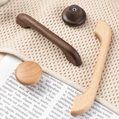 Curved solid wood cabinet pull with a matching round knob, arranged together from an overhead angle for comparison