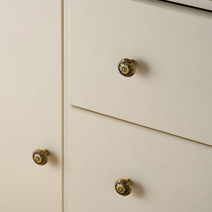 Ornate european brass cabinet pull and round knobs, shown clearly mounted on a finished cabinet front