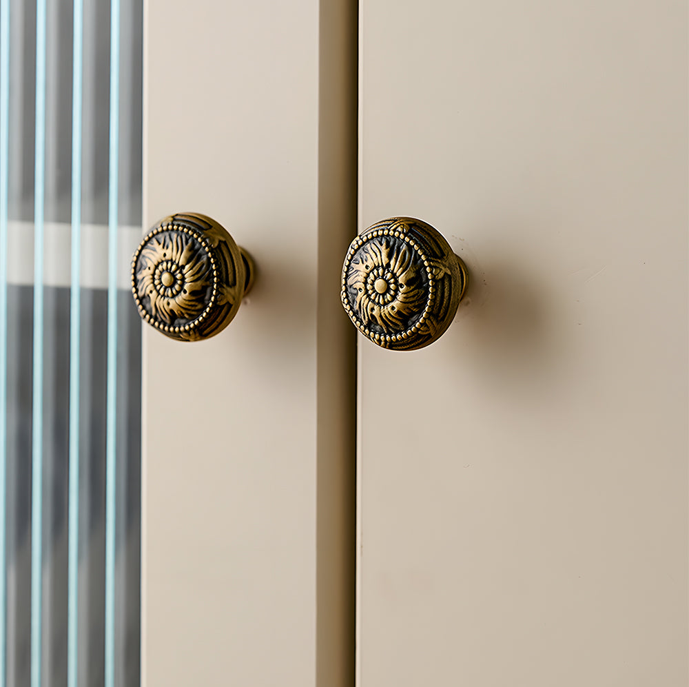 Ornate european brass cabinet pull and round knobs, shown from one angle mounted on a finished cabinet front