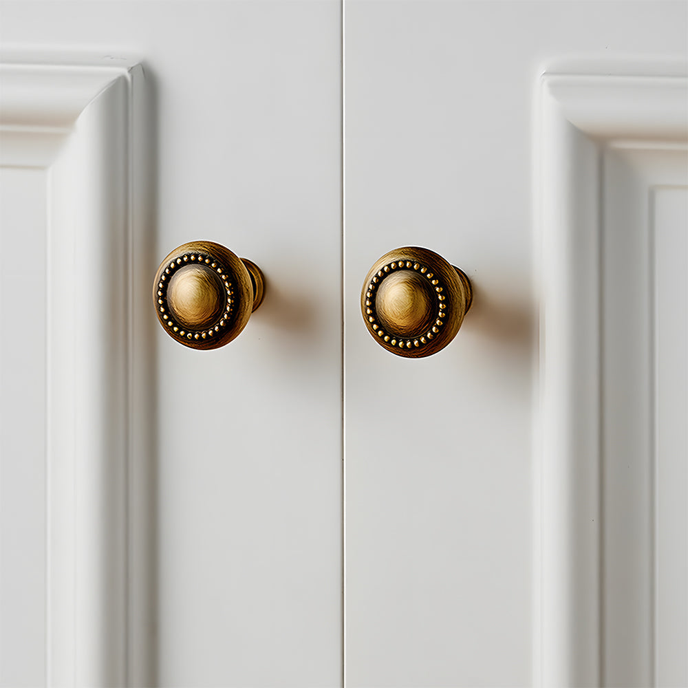 Ornate european brass cabinet pull and round knobs, pictured in one view mounted on a finished cabinet front
