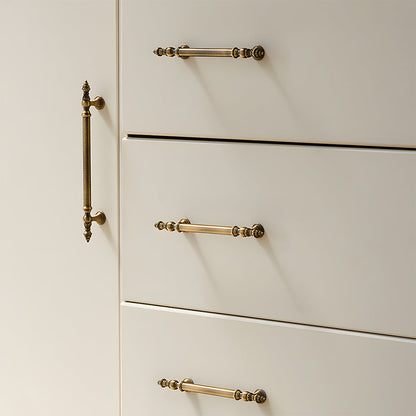 Ornate european brass cabinet pull and round knobs, shown from one angle installed on cabinetry in context