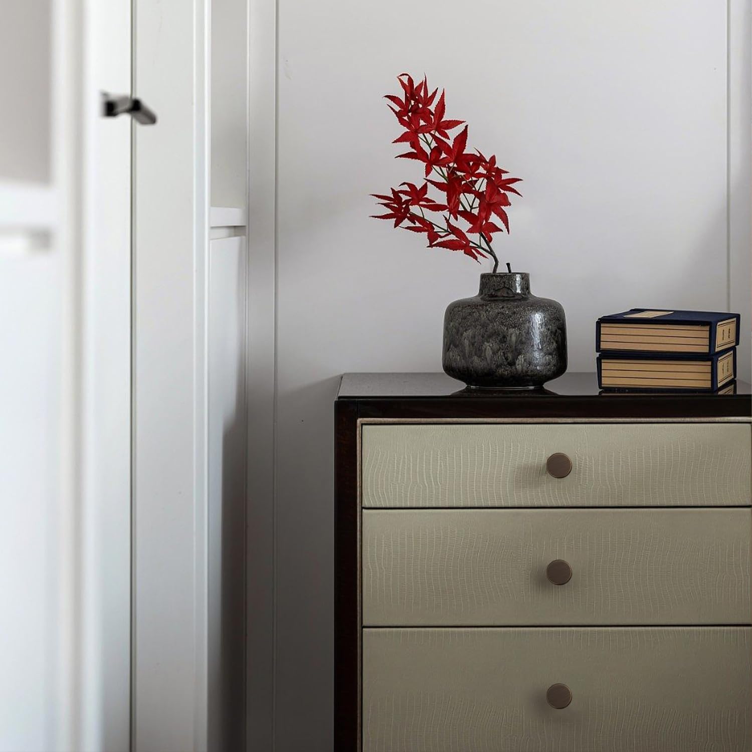 Faceted brass cabinet pull and round knob, shown in a focused view installed on cabinetry in context